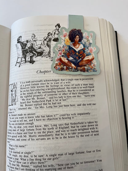 A handmade magnetic fold-over bookmark showing a Black woman reading with a flower
