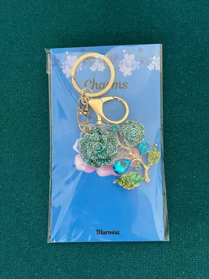 The blue rose charm keyring set with blue and green crystals, on its backing card